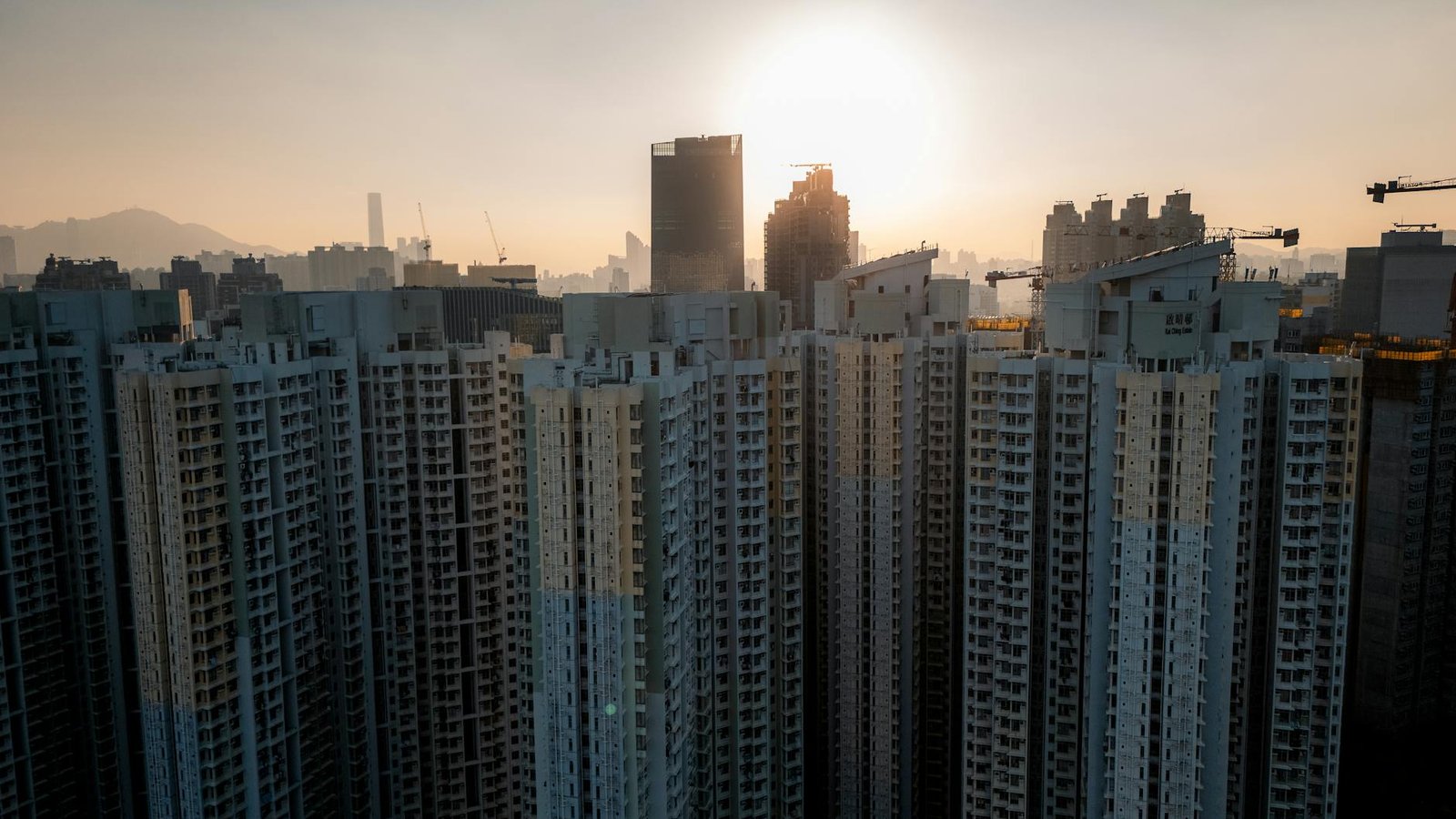 Dramatic view of Kowloon skyscrapers silhouetted against a warm sunset.