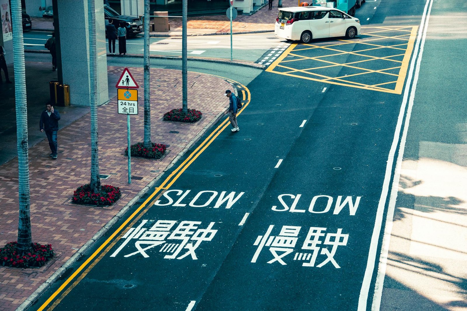 Street intersection with 'Slow' text in English and Chinese, featuring pedestrians and vehicles.