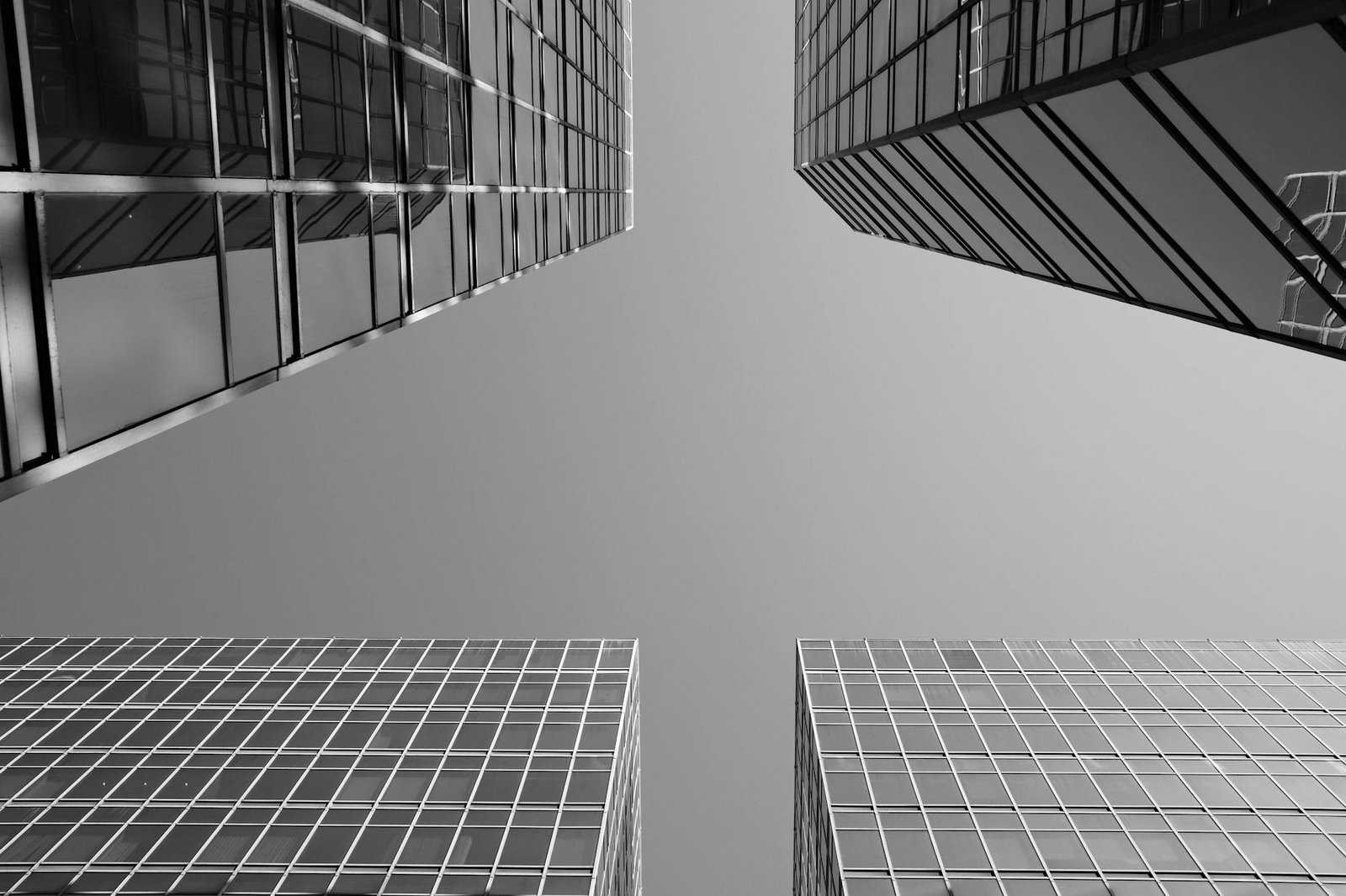 Black and white photo of modern skyscrapers in Hong Kong viewed from street level, showcasing sleek architectural design.