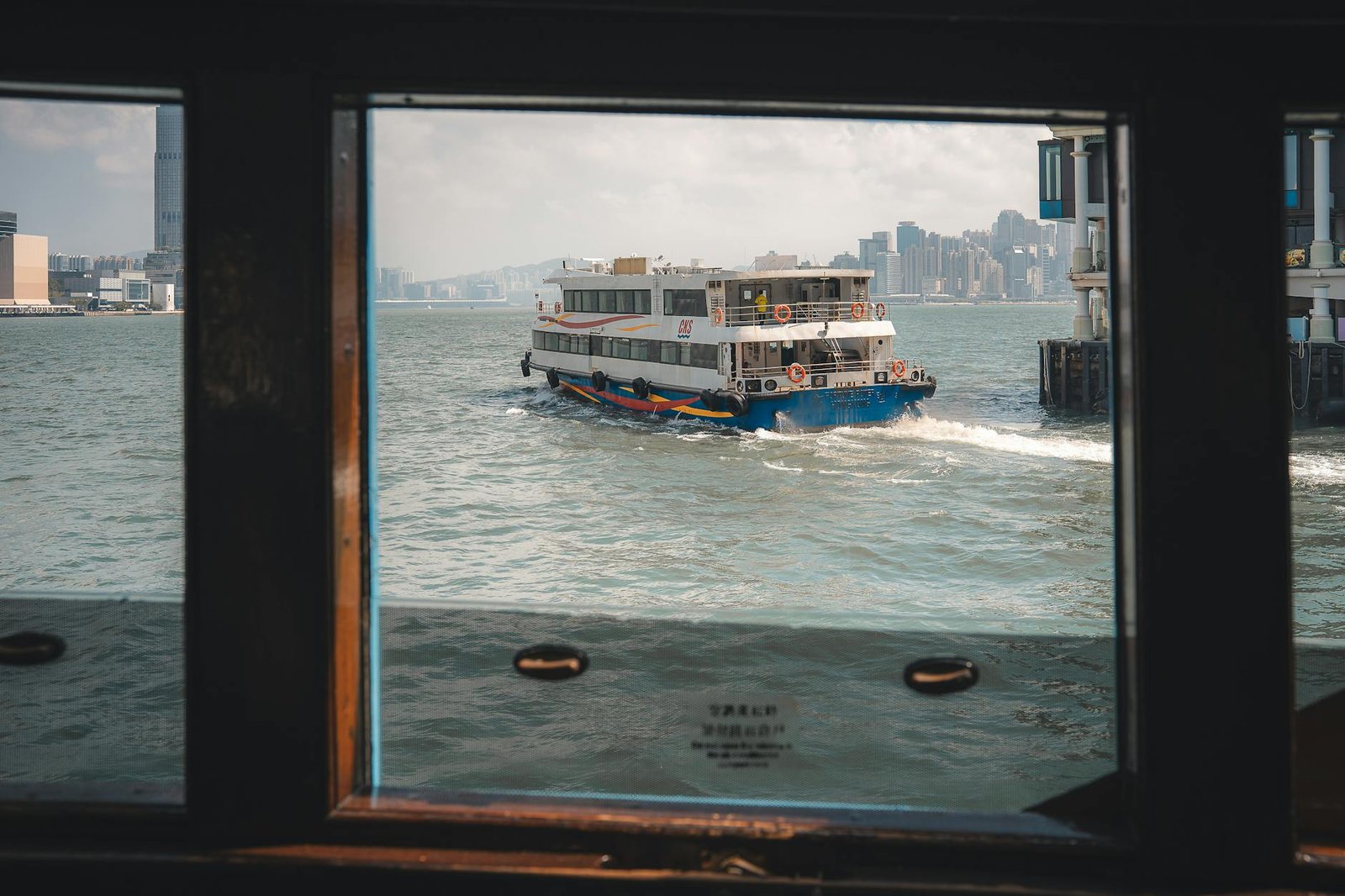 View of the Star Ferry crossing Victoria Harbour, iconic Hong Kong skyline in the background.