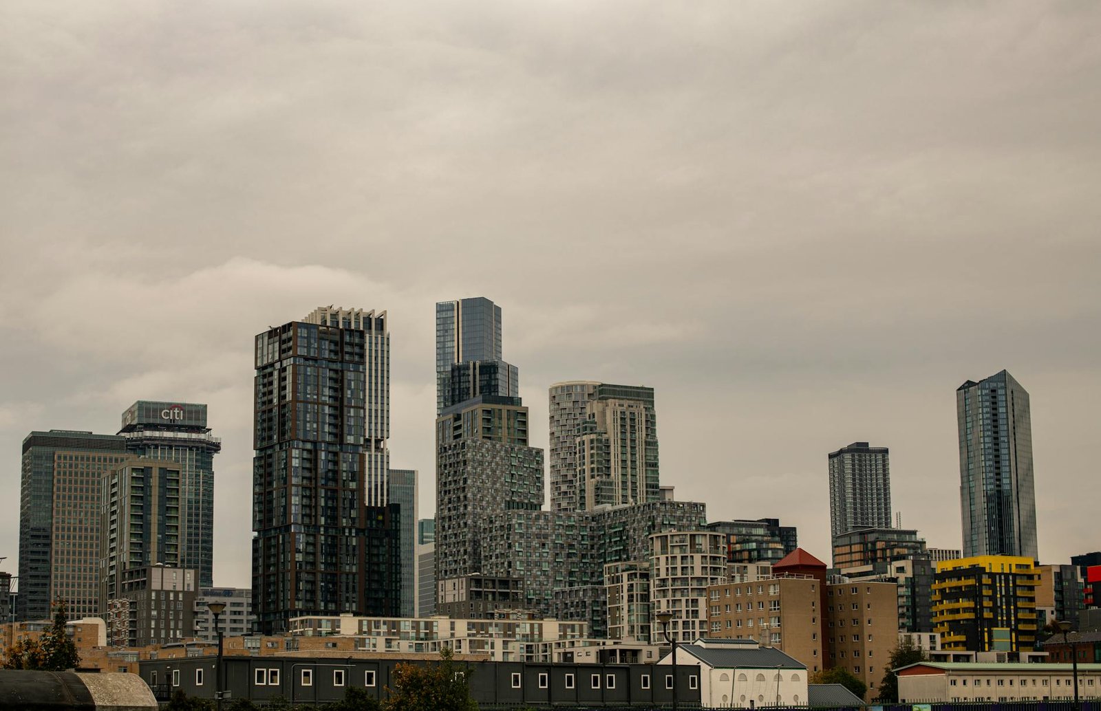 An urban cityscape of modern skyscrapers in Canary Wharf, London, on a cloudy day.