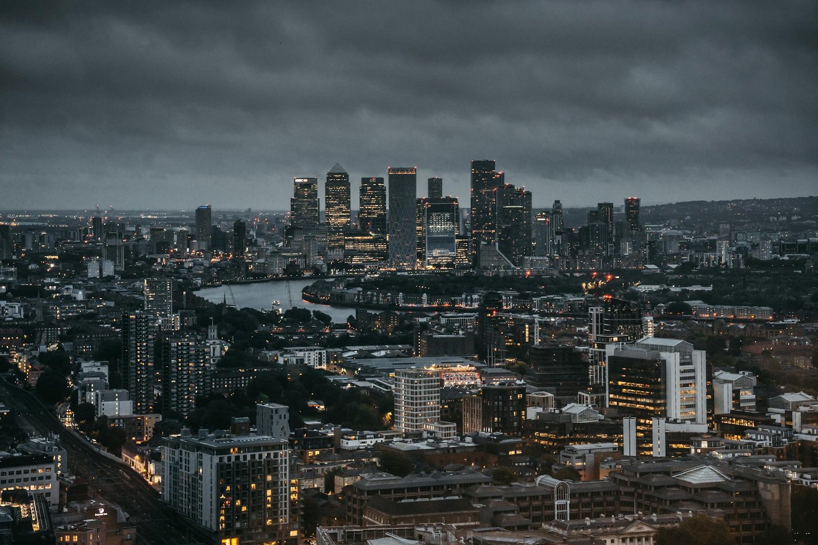 Stunning aerial view of a city's illuminated skyline at night, showcasing skyscrapers and a winding river.