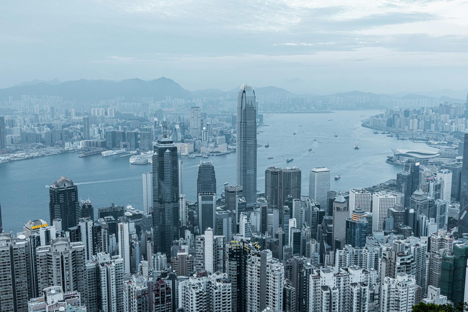 A stunning aerial view of Hong Kong's iconic skyline and Victoria Harbor on a cloudy day.