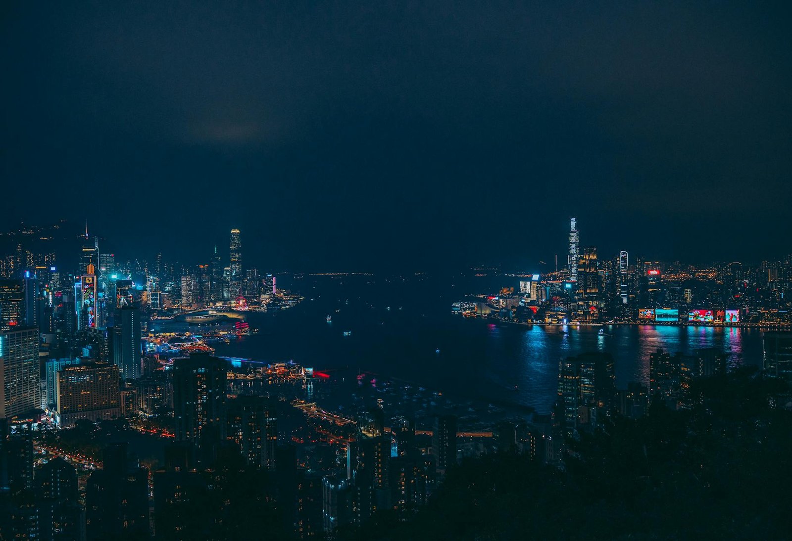 A stunning view of Hong Kong's illuminated skyline with reflections on the harbor at night.