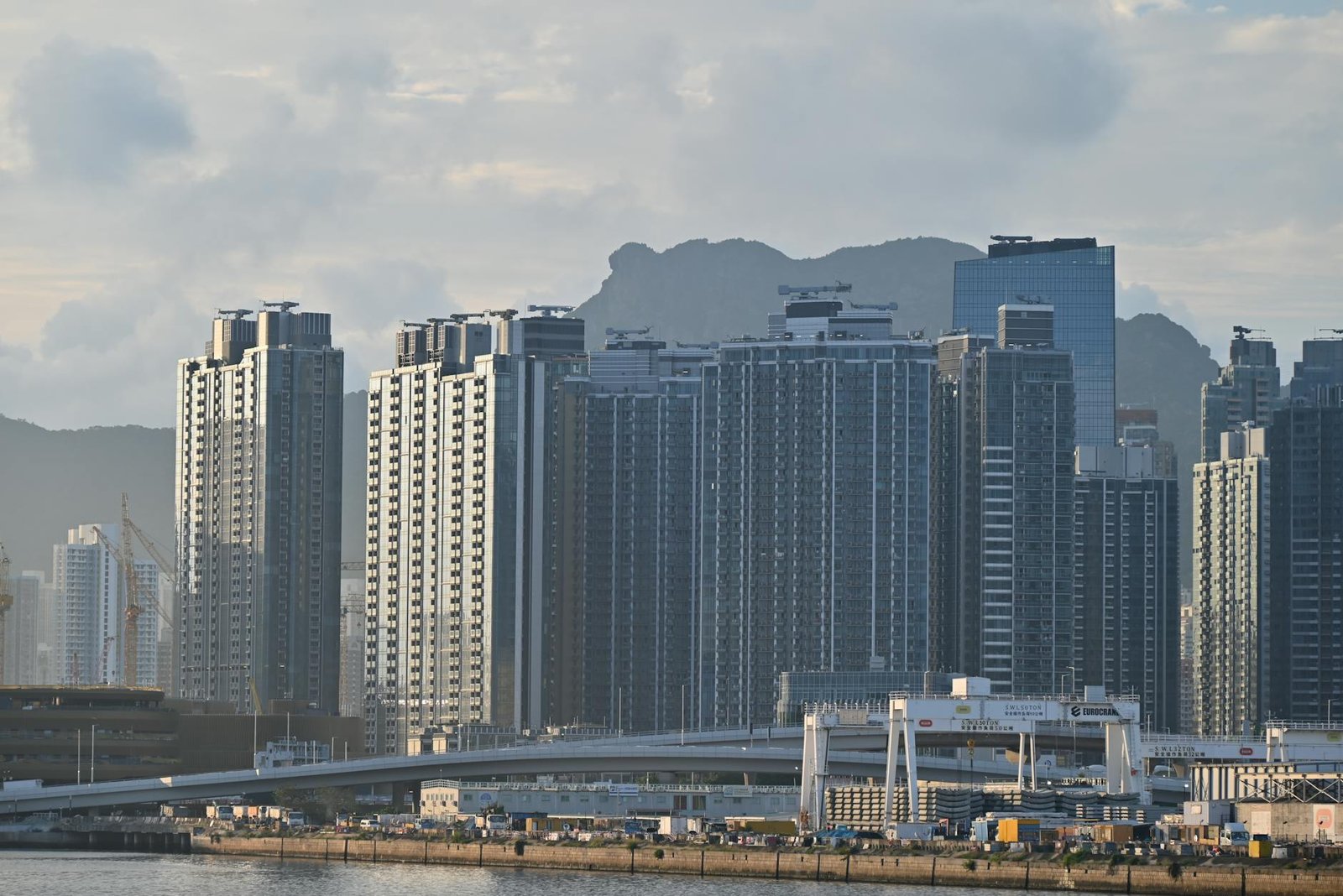 Cityscape featuring towering high-rise buildings against a mountainous backdrop.